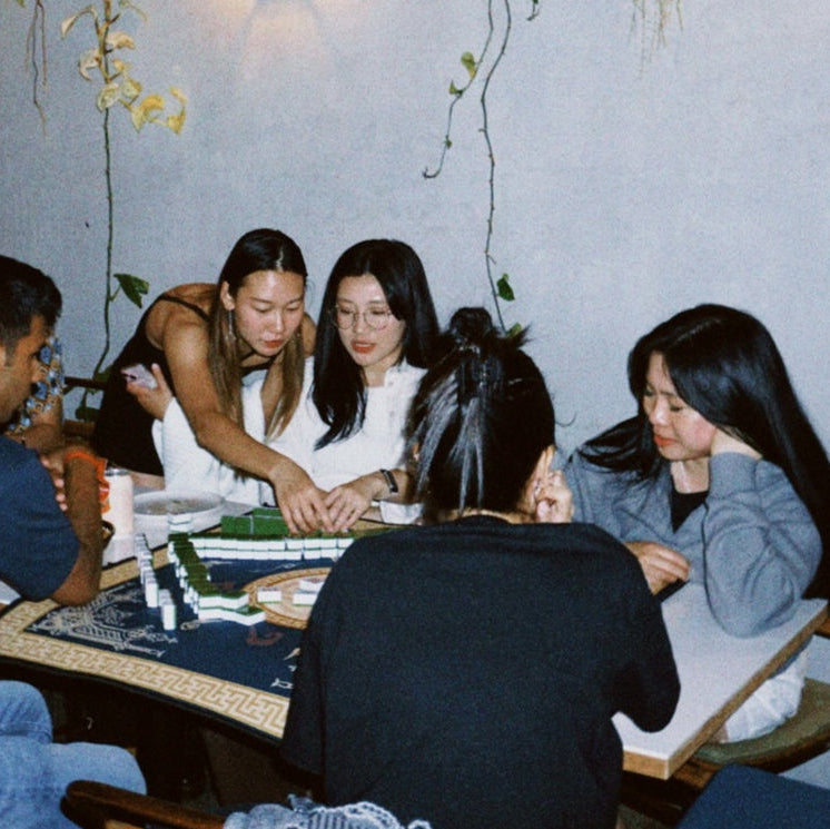 Group of people sitting around a table playing mahjong